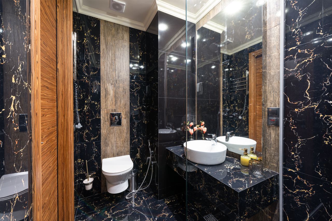 Creative design of bathroom with washstand between floral decoration and liquid soap reflecting in mirror under glowing lamps